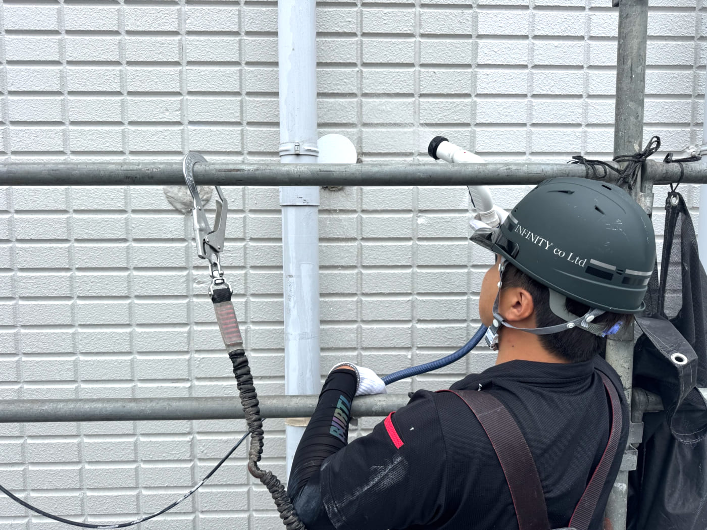 ロープで降下しながら外壁を洗浄する作業員
