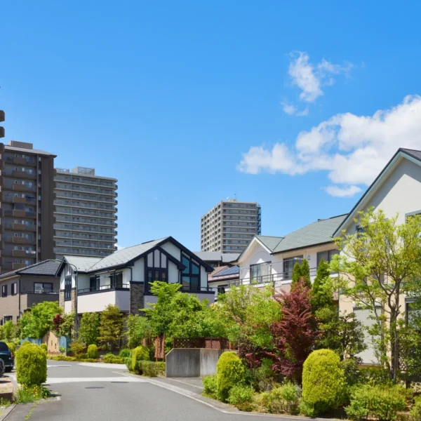 青空の下の、戸建て住宅とマンションが並ぶ住宅街